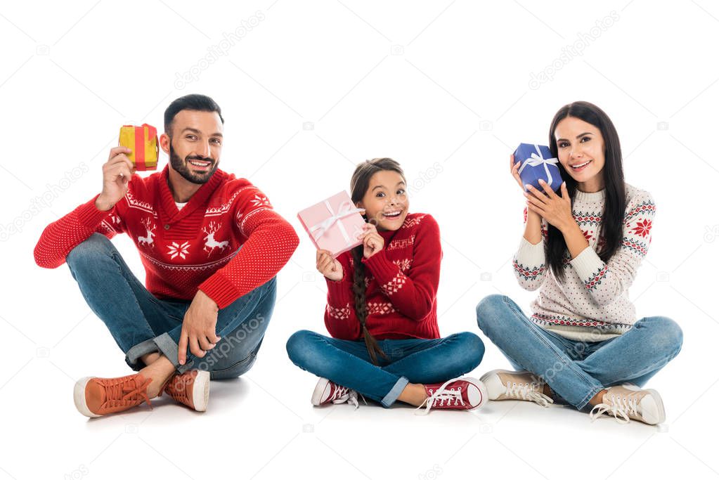 cheerful family in sweaters holding gifts on white 
