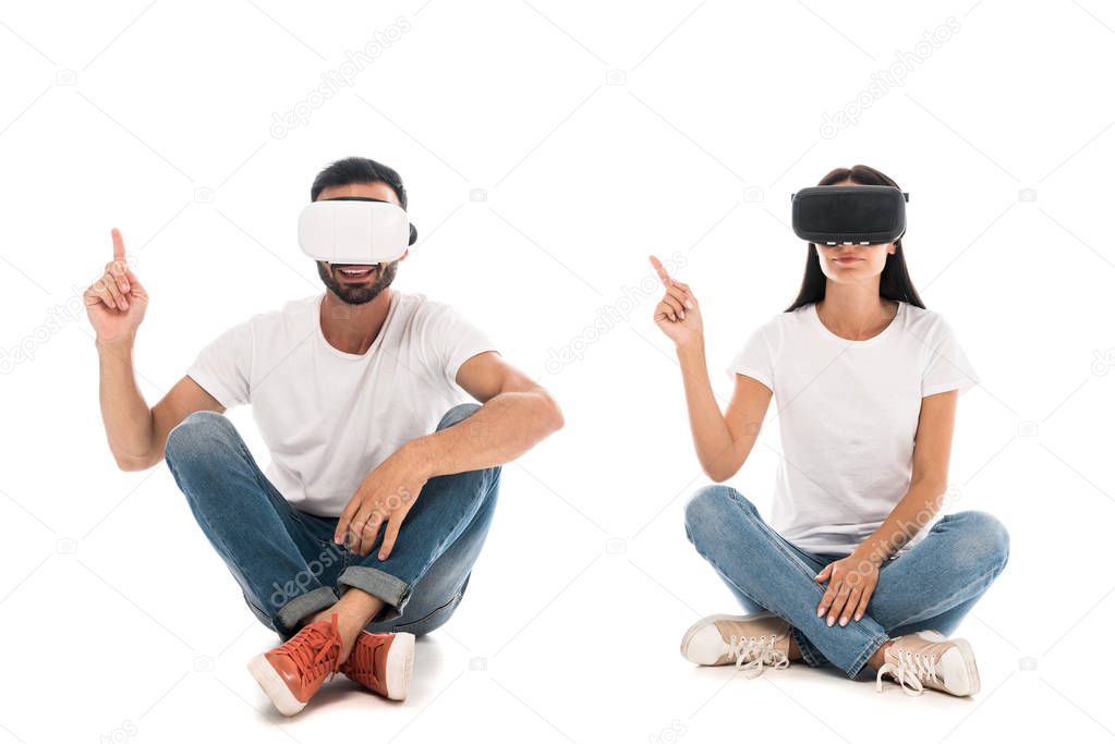 happy man sitting with woman while using virtual reality headsets and pointing with fingers on white 