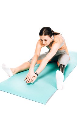 Beyazın üzerinde izole edilmiş fitness paspası üzerinde gerinen engelli sporcu kadının genel görünümü