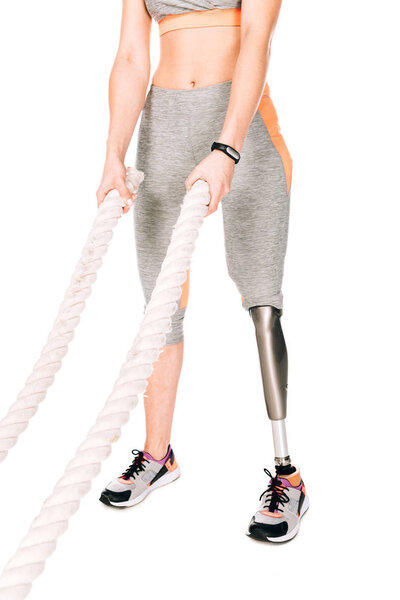 cropped view of disabled sportswoman with prosthetic leg training with ropes isolated on white