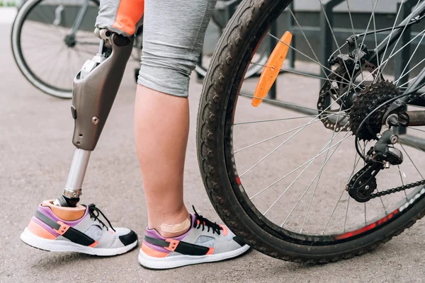 路上で自転車を持っている障害者スポーツ女性の一部を見ると — ストック写真