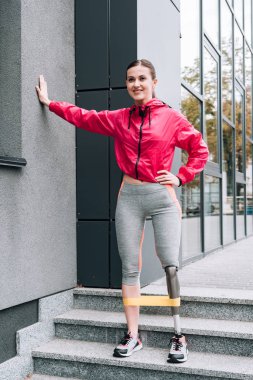 Gülümseyen engelli kadın sporcu eğitiminin sokaktaki direniş bandıyla tam boy görünümü