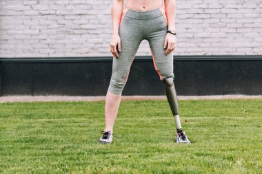 Çimlerin üzerinde fitness takip cihazı olan engelli sporcunun kısmi görüntüsü