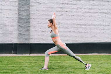 Çimenlerde yoga yapan engelli sporcu kadının yan görüntüsü