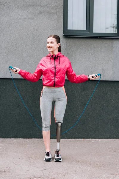 路上でロープをスキップして笑顔の障害者スポーツ女性の完全な長距離ビュー — ストック写真