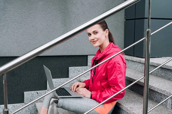 Lächelnde Behindertensportlerin Mit Laptop Auf Der Treppe Auf Der Straße — Stockfoto