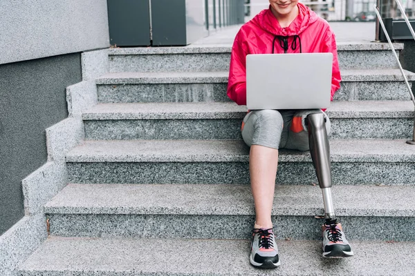 Cropped View Smiling Disabled Sportswoman Using Laptop While Sitting Stairs — ストック写真