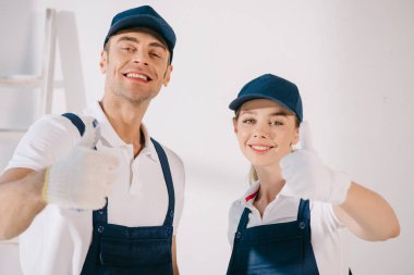 İki neşeli ressam kameraya gülümserken başparmağını kaldırıyor.