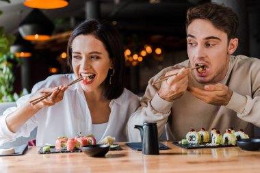 Genç adam ve kadın suşi barında lezzetli suşi yiyorlar.