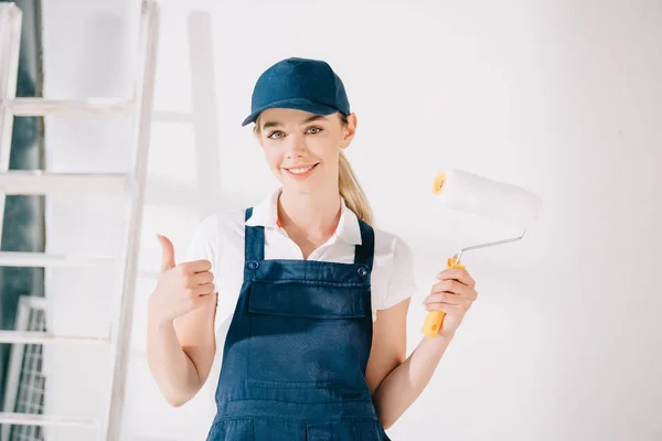 Atractivo Joven Pintor Uniforme Sonriendo Cámara Mientras Sostiene Rodillo Pintura — Foto de Stock