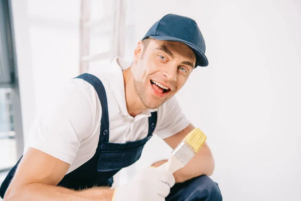 Alegre Joven Pintor Uniforme Sosteniendo Pincel Sonriendo Cámara — Foto de Stock