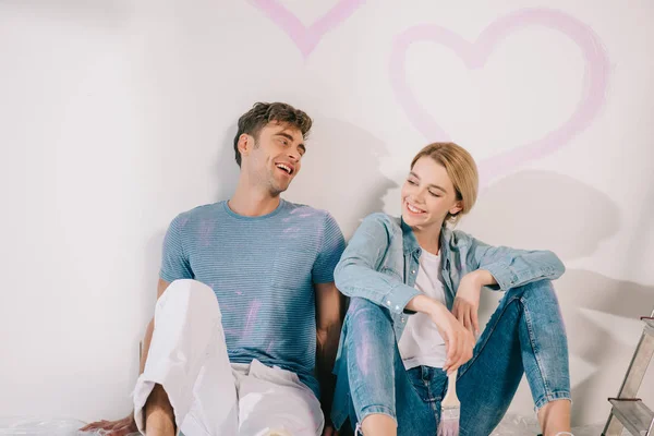 Feliz Jovem Casal Sentado Parede Branca Sob Coração Rosa Desenhado — Fotografia de Stock