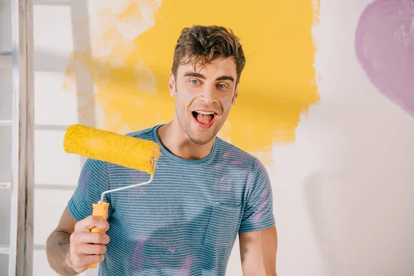 Cheerful Young Man Holding Yellow Paint Roller While Looking Camera — Stock Photo, Image