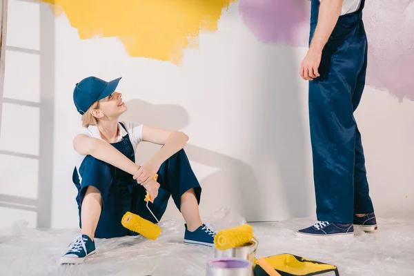 Atractivo Joven Pintor Uniforme Sentado Suelo Mirando Hombre Uniforme — Foto de Stock