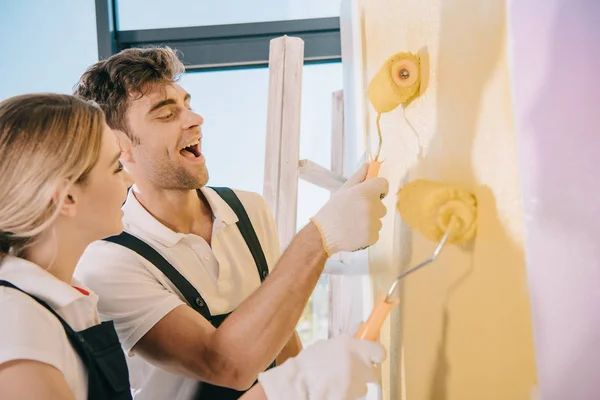 Dos Jóvenes Pintores Pintando Pared Amarillo Rosa Con Rodillos Pintura —  Fotos de Stock