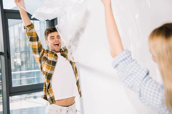 Happy Young Man Holding Cellophane Girlfriend While Preparing Room Repair — Stock Photo, Image