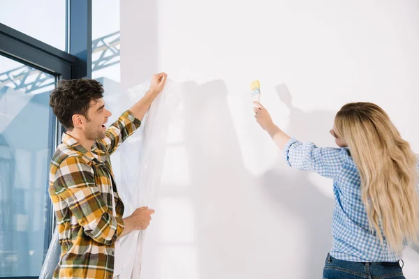 Young Man Holding Cellophane While Girlfriend Standing Yellow Paintbrush — Stock Photo, Image