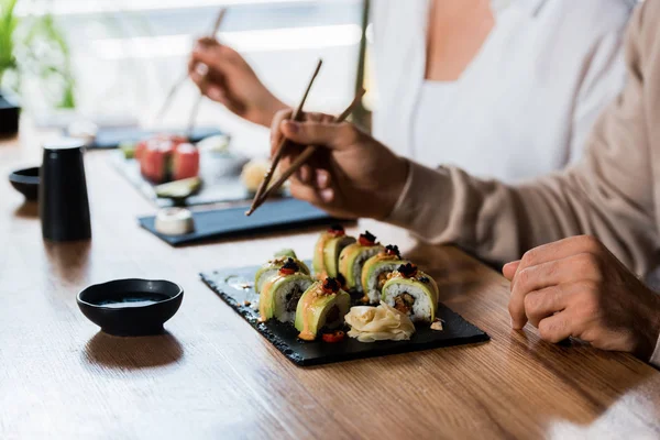 Vista Cortada Homem Segurando Pauzinhos Perto Rolos Sushi Mulher — Fotografia de Stock