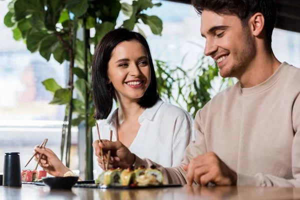 Enfoque Selectivo Mujer Feliz Sosteniendo Palillos Con Sushi Mirando Hombre —  Fotos de Stock