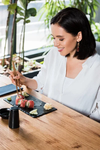 Jovem Mulher Feliz Segurando Pauzinhos Perto Sushi Saboroso Restaurante — Fotografia de Stock