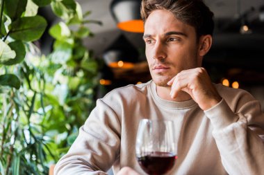 selective focus of man sitting in restaurant with glass of red wine  clipart