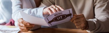 panoramic shot of woman pointing with finger at menu near man  clipart
