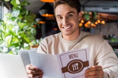 selective focus of positive man holding menu in restaurant  clipart