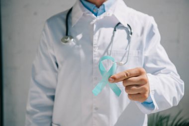Mavi farkındalık kurdelesi taşıyan beyaz önlüklü doktorun kısmi görüntüsü