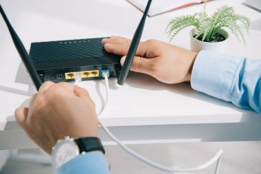 partial view of businessman plugging router on office desk clipart