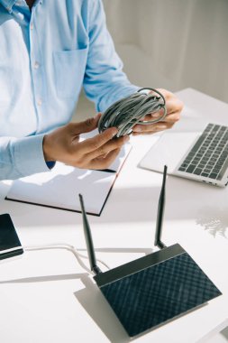Modem ve dizüstü bilgisayarın yanında kablo tutan işadamlarının kırpılmış görüntüsü