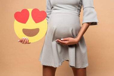 Kyiv, Ukrayna - 1 Ağustos 2019: Gri elbiseli hamile kadının bej arka planda gözleri gülen bir gülüşü vardı. 