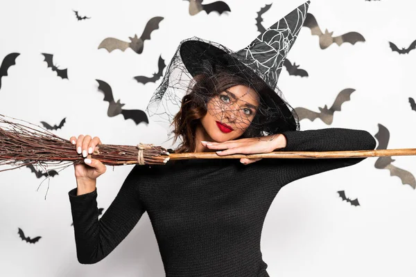 attractive woman in witch hat holding broom in Halloween