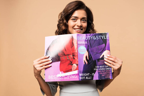 pregnant woman in grey dress holding beauty and style magazine on beige background 