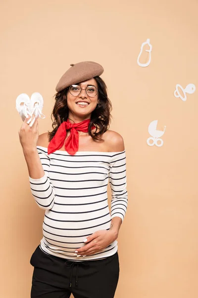 Pregnant French Woman Beret Holding Shoes Beige Background — Stock Photo, Image