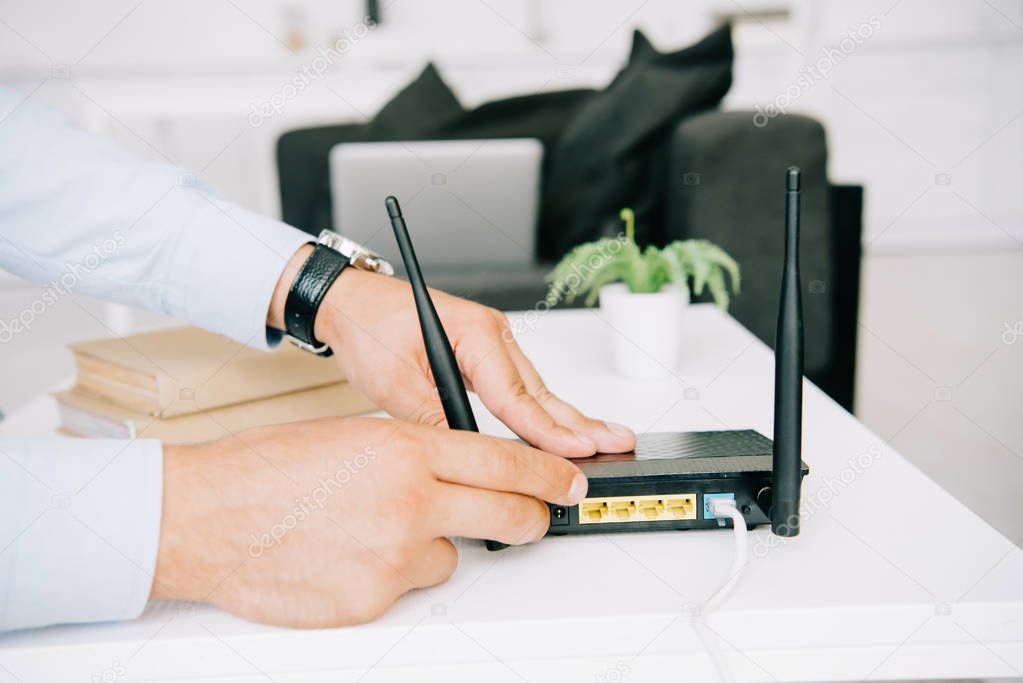 partial view of businessman adjusting router on white table