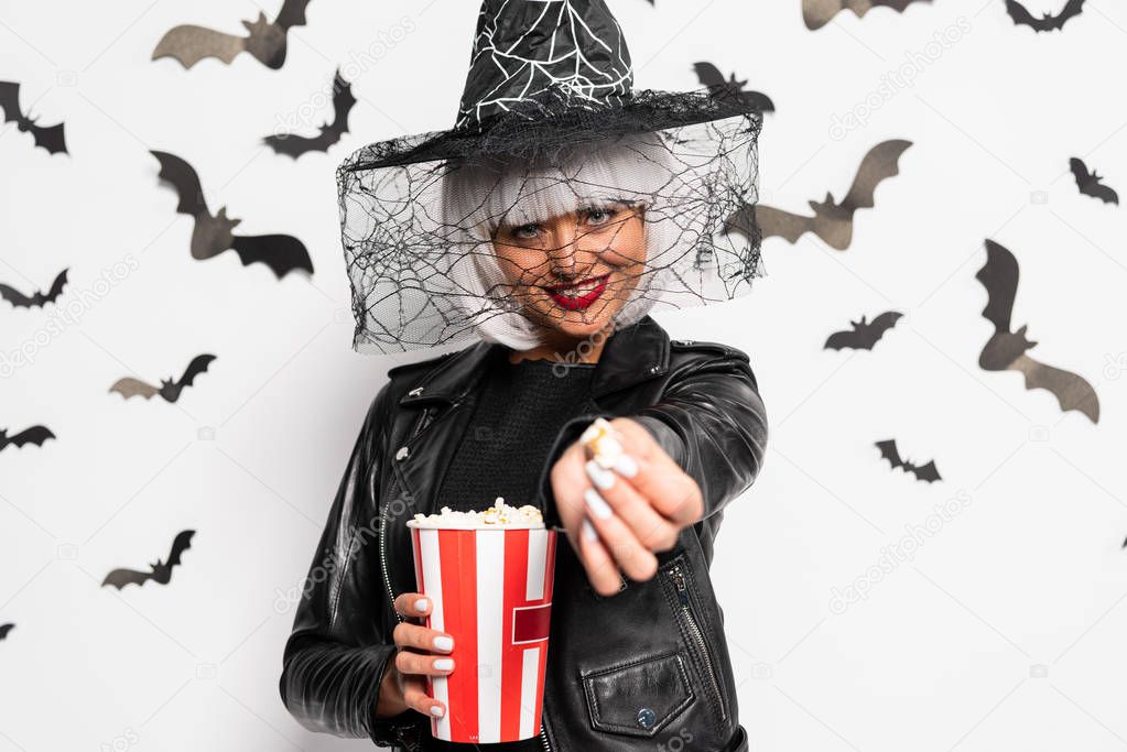 smiling woman in witch hat and wig holding popcorn in Halloween