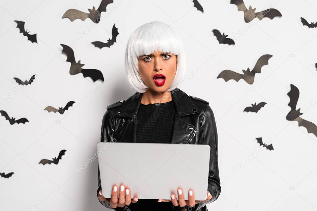 shocked woman in white wig holding laptop in Halloween