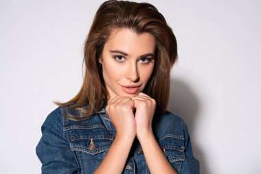 Neşeli genç bir kadın beyaz kameraya bakıyor. 