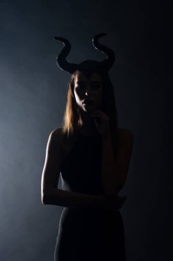 silhouette of young woman with horns standing on black  clipart
