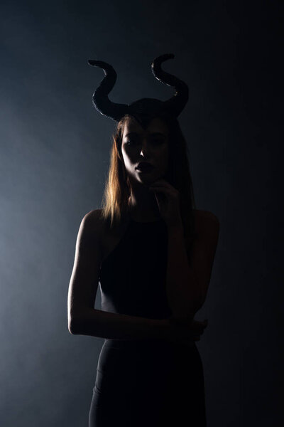 silhouette of young woman with horns standing on black 