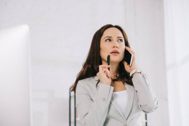 Genç, düşünceli sekreter ofisteki akıllı telefondan konuşurken başka tarafa bakıyor.