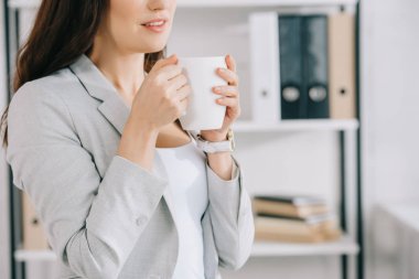 Ofiste kahve fincanı tutan genç sekreter manzarası.