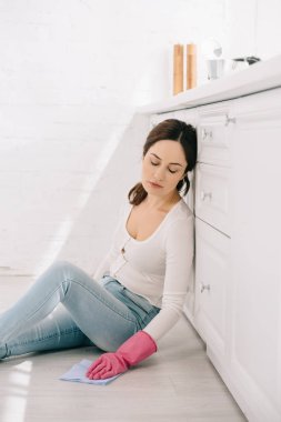 exhausted housewife sitting on floor in kitchen with closed eyes