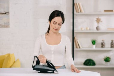 Güzel ev hanımı ütü yaparken gülümsüyor.