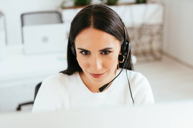 selective focus of attractive broker in headset working in call center  clipart