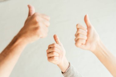 cropped view of brokers showing thumbs up on white  clipart