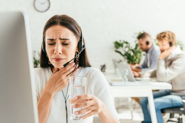 Boğazı ağrıyan ve bir bardak su tutan hasta simsarın seçici odağı. 