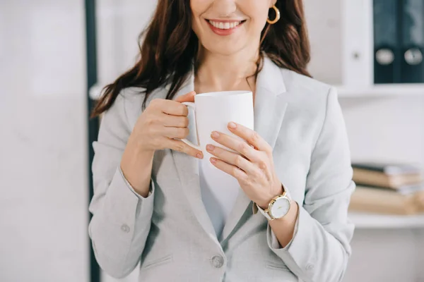 オフィスでコーヒーカップを持っている秘書の笑顔を切り取った — ストック写真