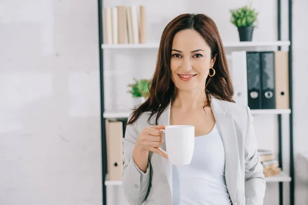 Güzel Mutlu Sekreter Kahve Fincanı Tutarken Kameraya Bakıyor — Stok fotoğraf