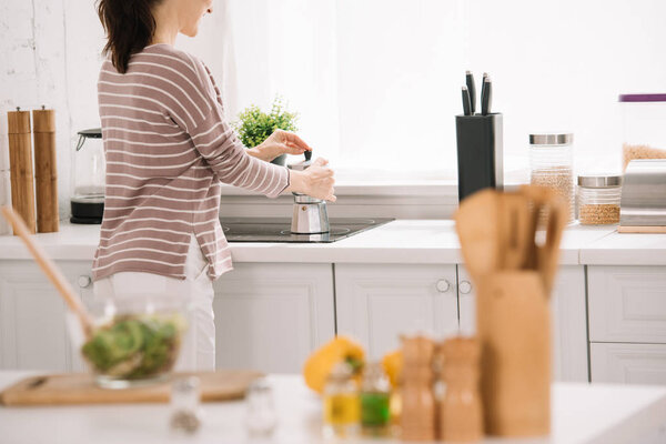 cropped view of young woman preparing coffee in geyser coffee maker
